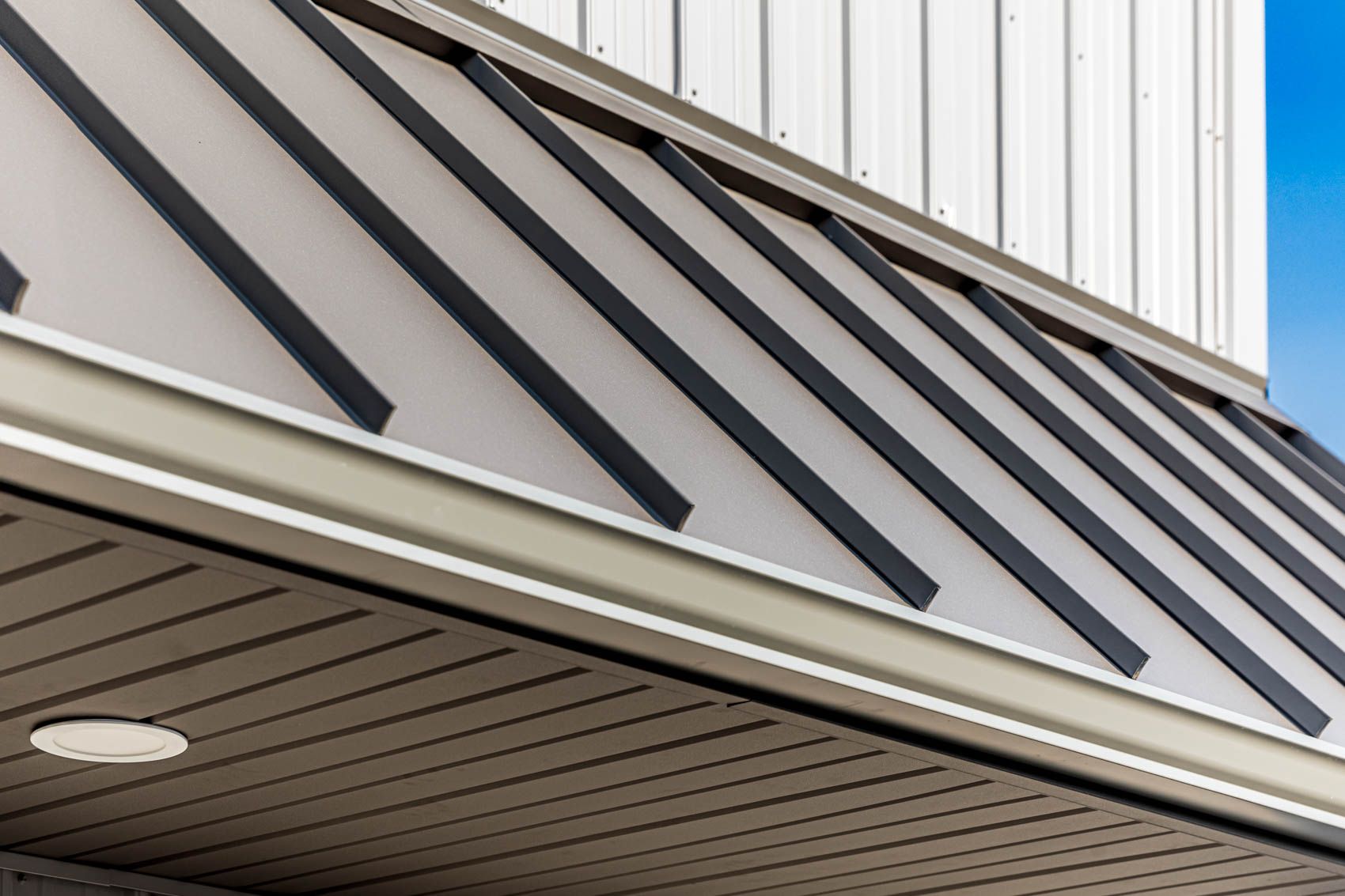 Beige and black metal awning with corrugated ceiling, attached to a white building.