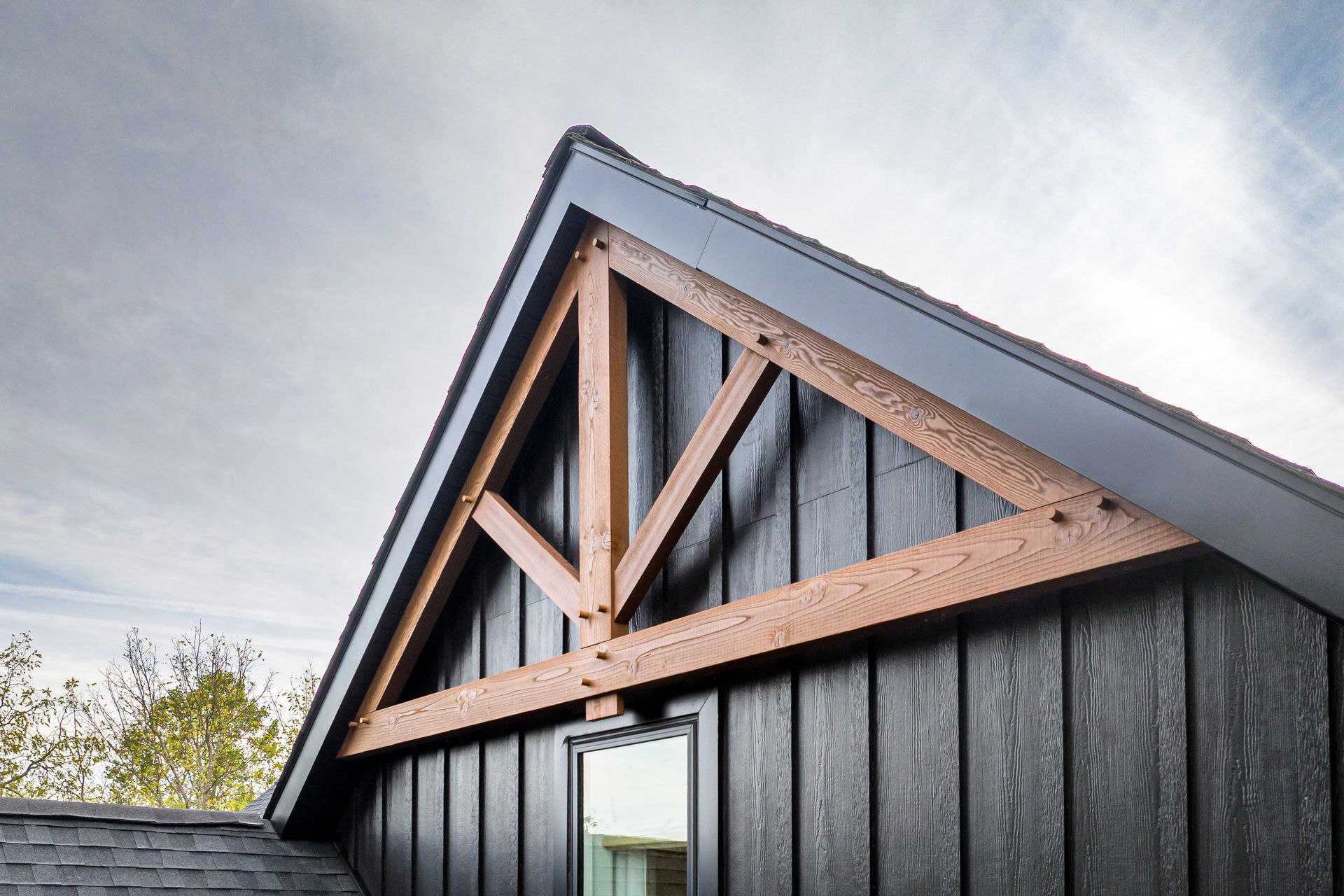 Black house exterior with a wooden triangular truss.