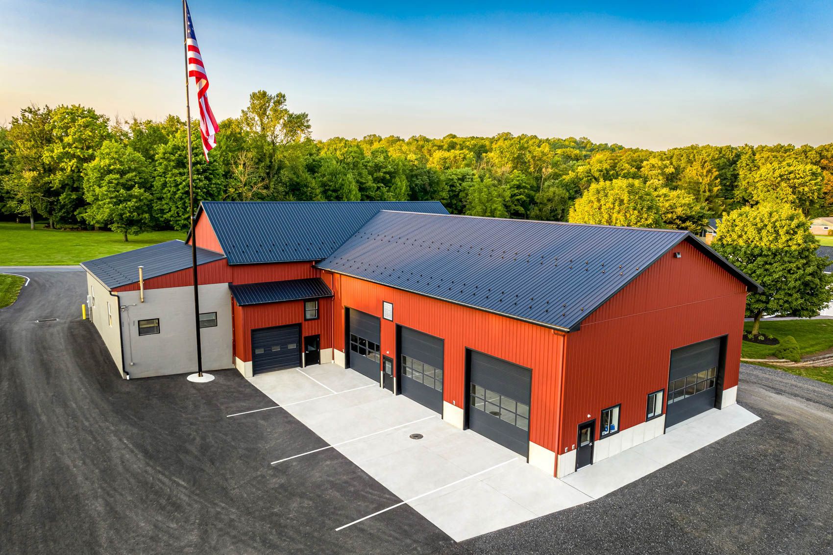 Fire station with red exterior, gray garage doors, and an American flag.