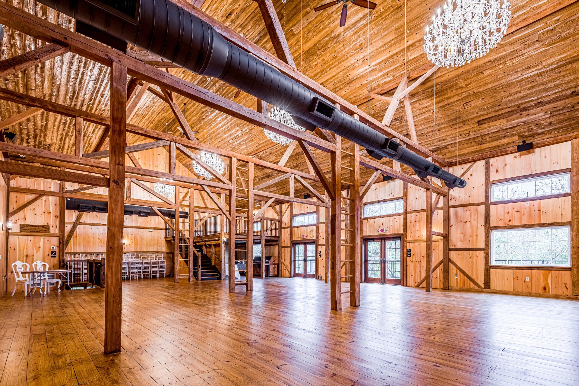 Large wooden event space with a mezzanine, wooden floor, and decorative lighting.