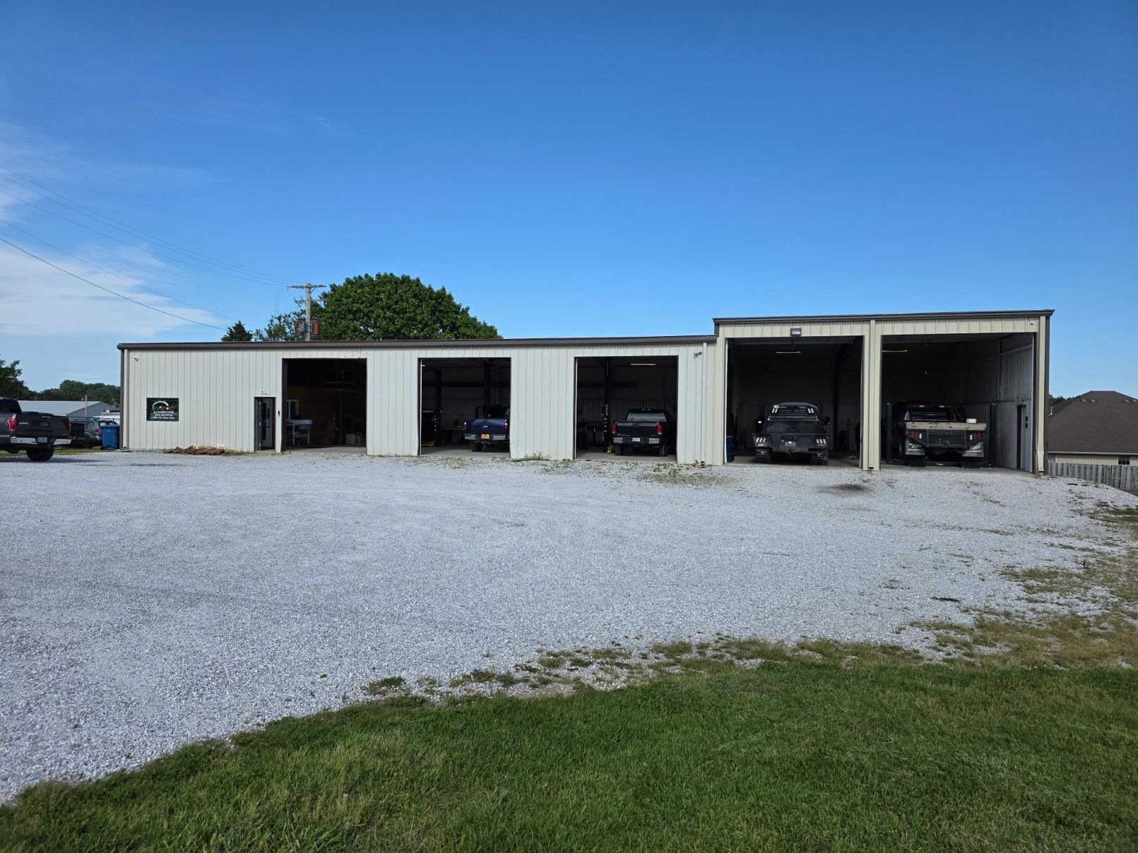Classic cars parked outside a garage, including red, blue, turquoise, and gray cars on gravel. | C & C Automotive
