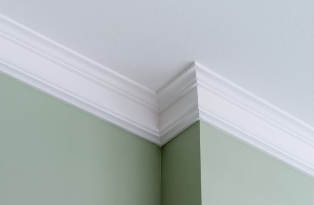 White crown molding at the corner of a light green wall and white ceiling.