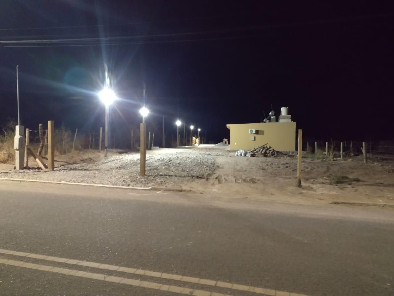 Escena nocturna: camino iluminado que conduce a un edificio beige con estructuras de servicios públicos