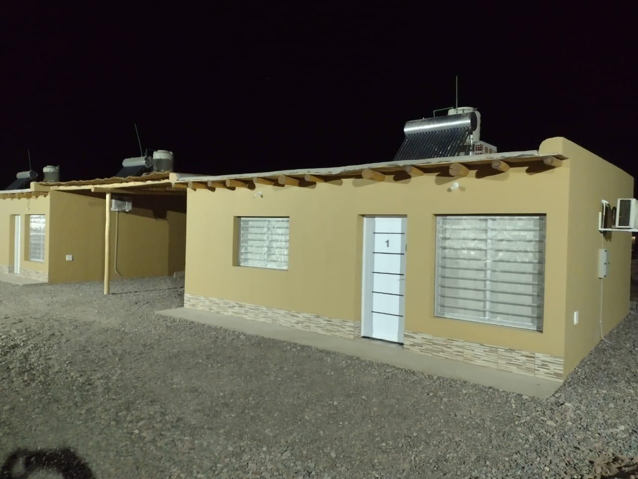 Dos edificios de una sola planta, de color canela, de noche. Cada uno tiene paneles solares 