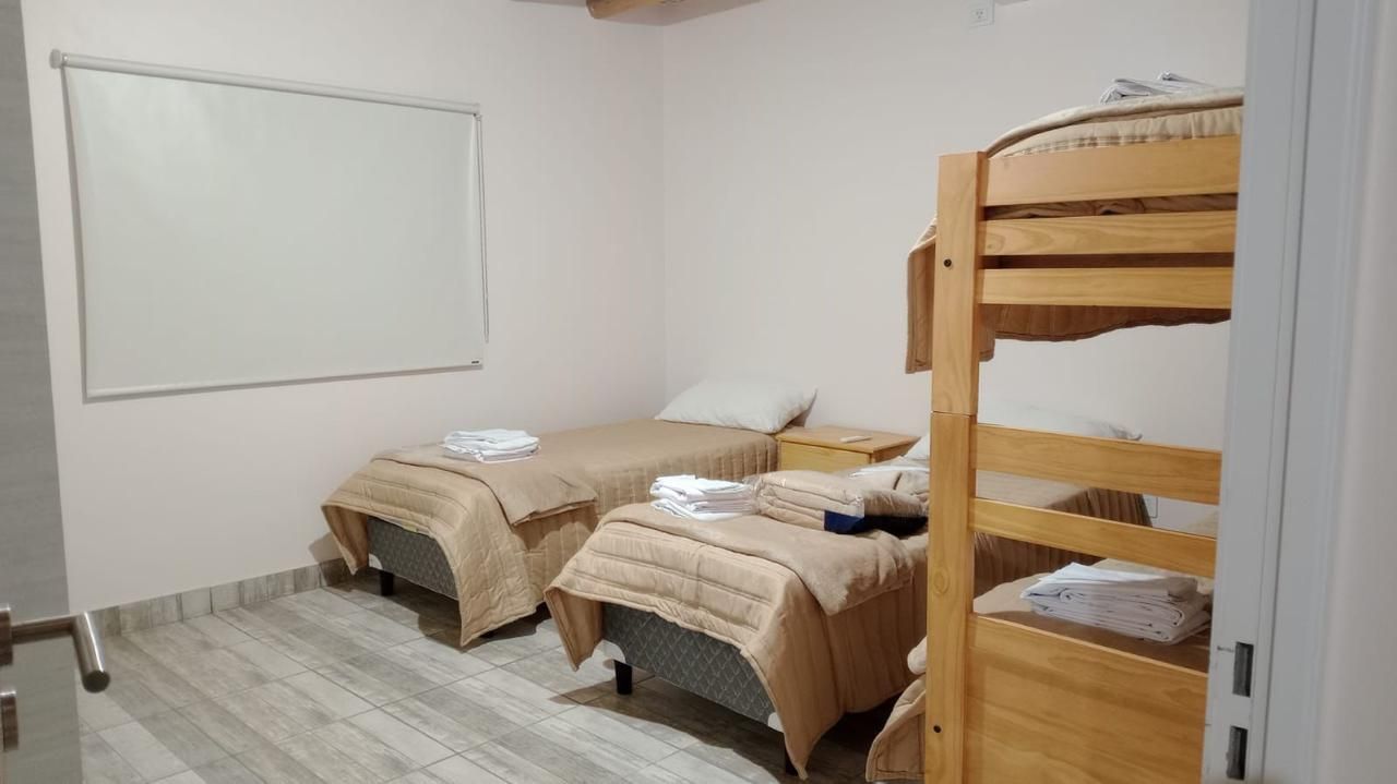 Dormitorio con literas y dos camas individuales con ropa de cama de color marrón; paredes blancas.