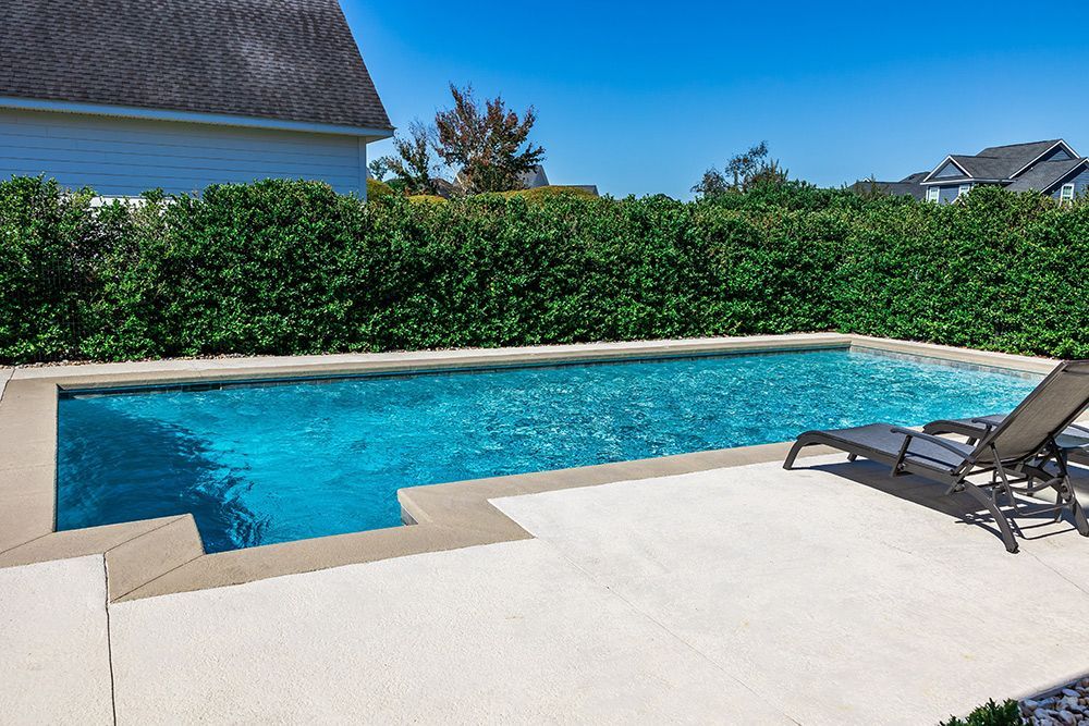 Clean backyard swimming pool with clear blue water and concrete deck.
