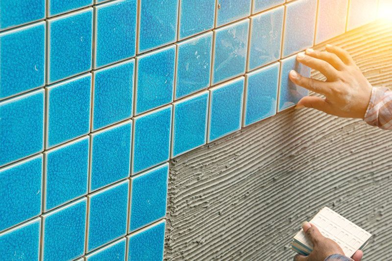 Swimming pool tile repair and installation during pool renovation service.