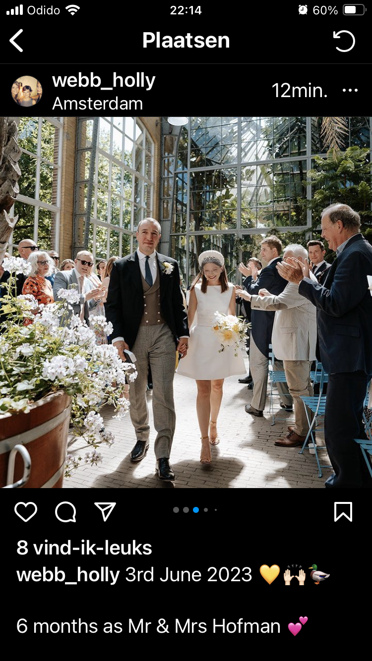 Pasgetrouwden wandelen, omringd door gasten in een kasachtige omgeving.