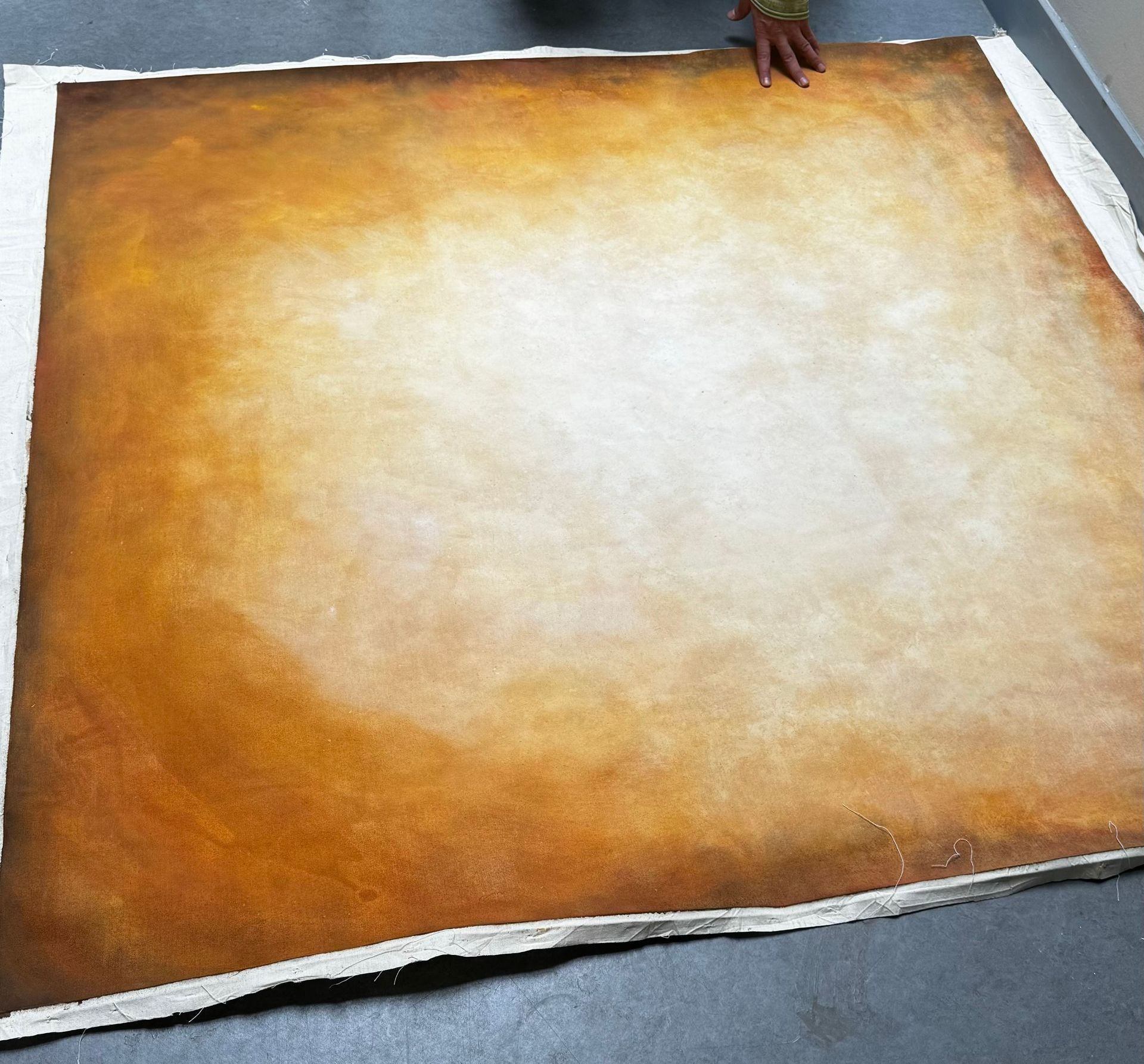 Bruin oranje en wit gemeleerd op een groot vierkant doek, vastgehouden door handen.