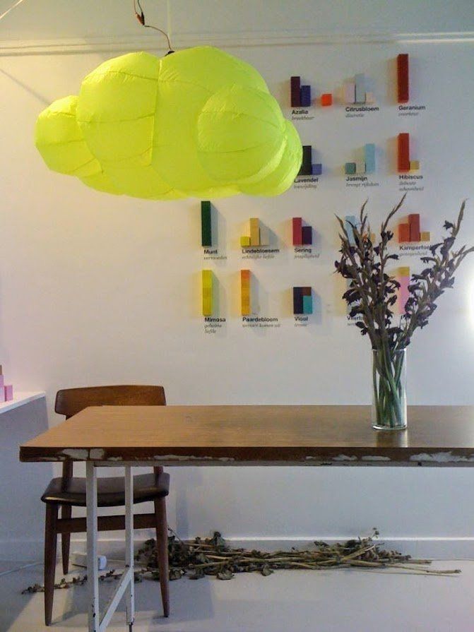 Interieur met een grote houten tafel, stoel en wolkvormige lamp. Kleurrijke staafdiagramkunst aan de muur.