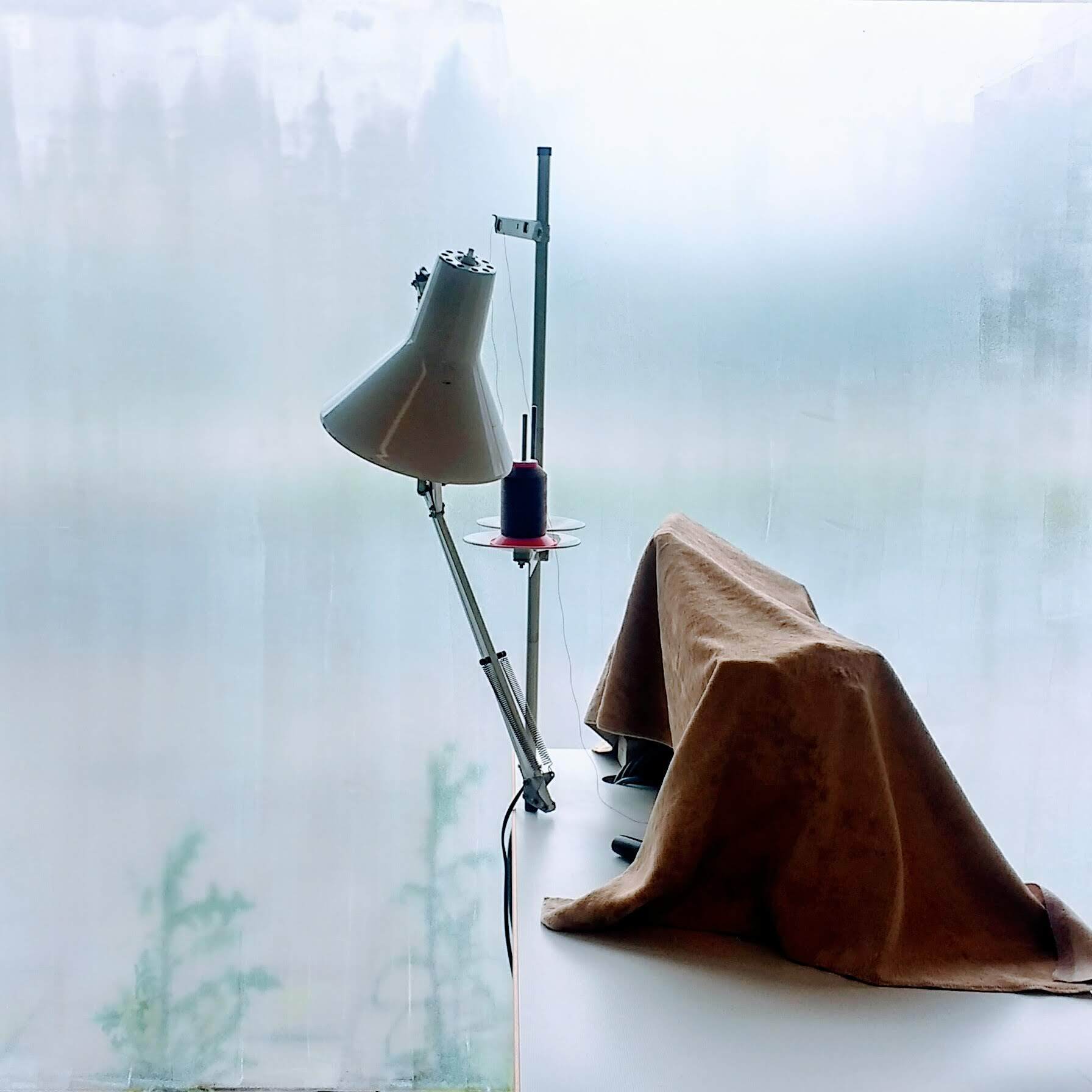 Naaimachine met een lamp en stof voor een wazig raam.