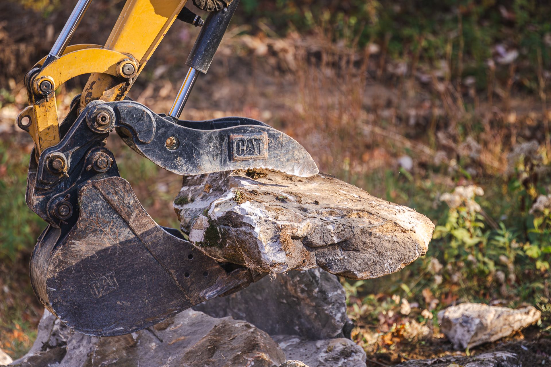 A bulldozer is scooping a large rock out of the ground.
