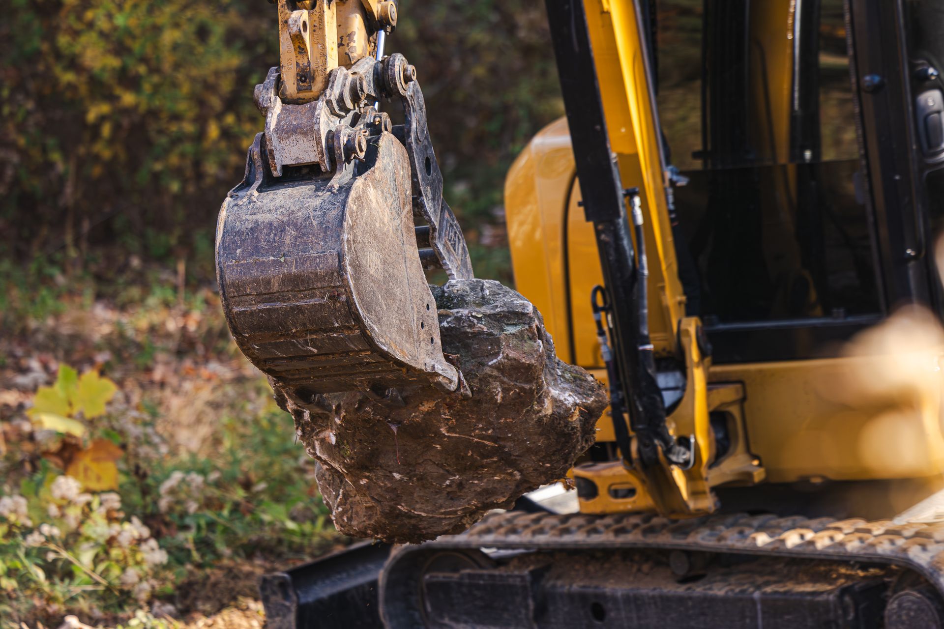 A yellow and black excavator is digging a hole in the ground.