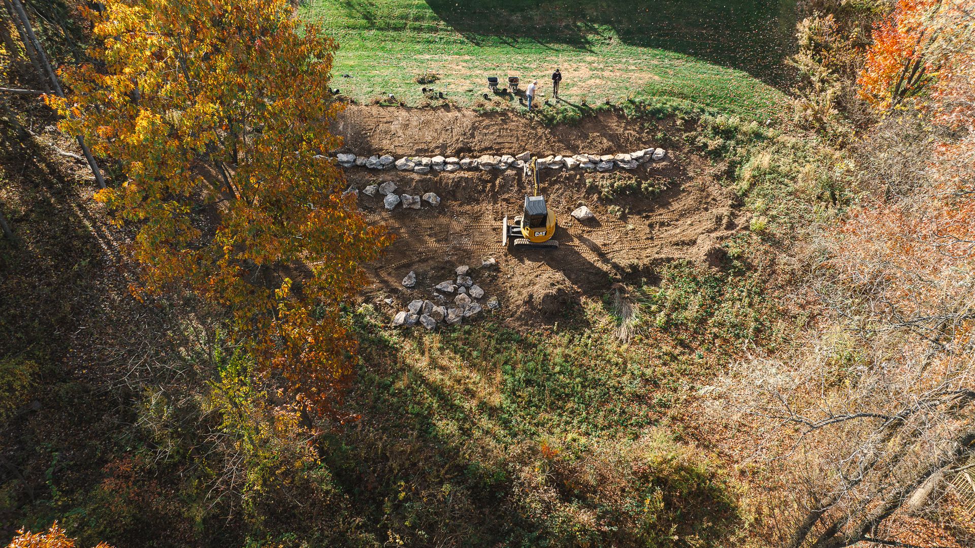 An aerial view of a field with trees and a house in the middle of it.