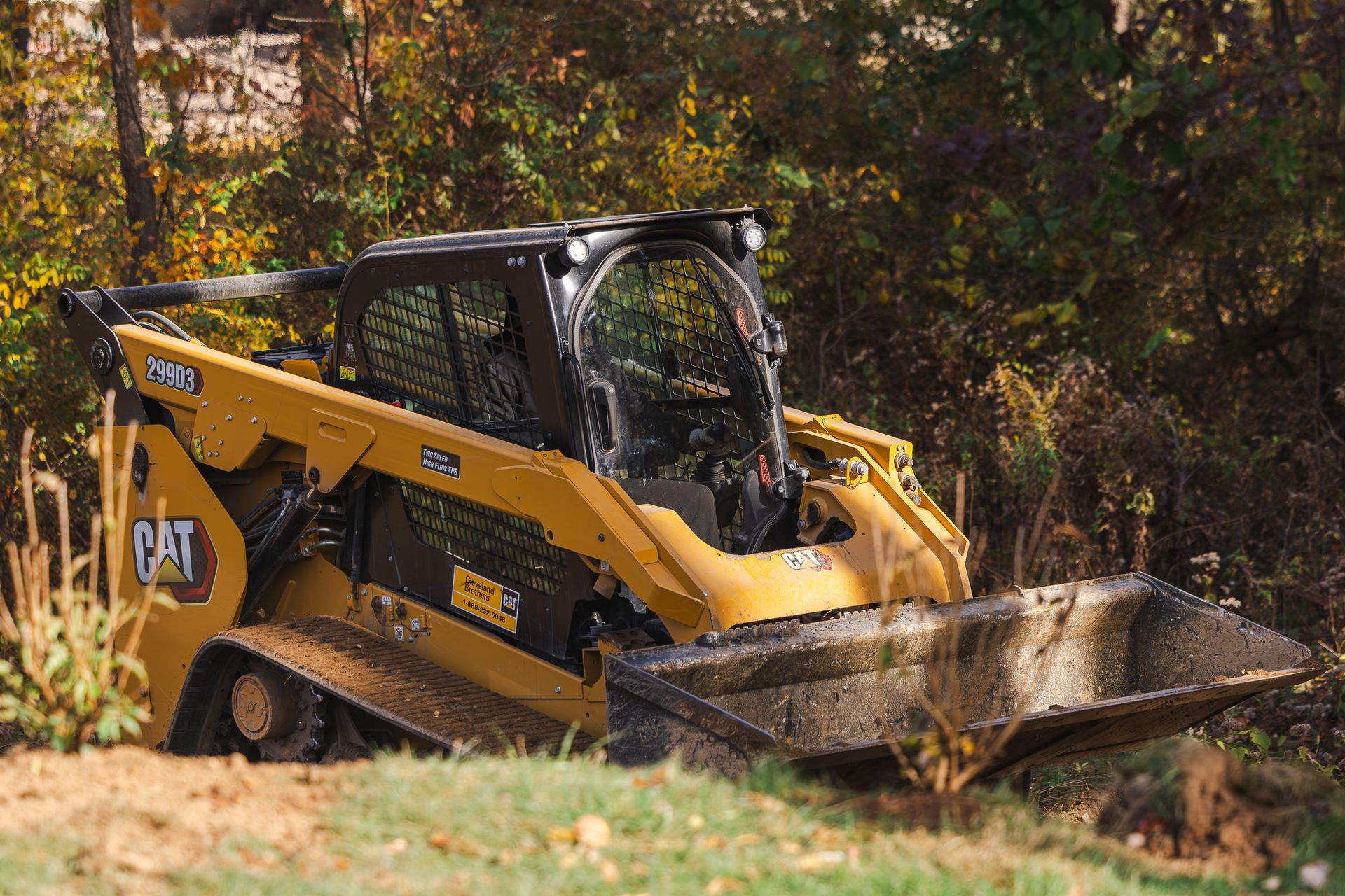A yellow cat bulldozer is driving down a dirt road.