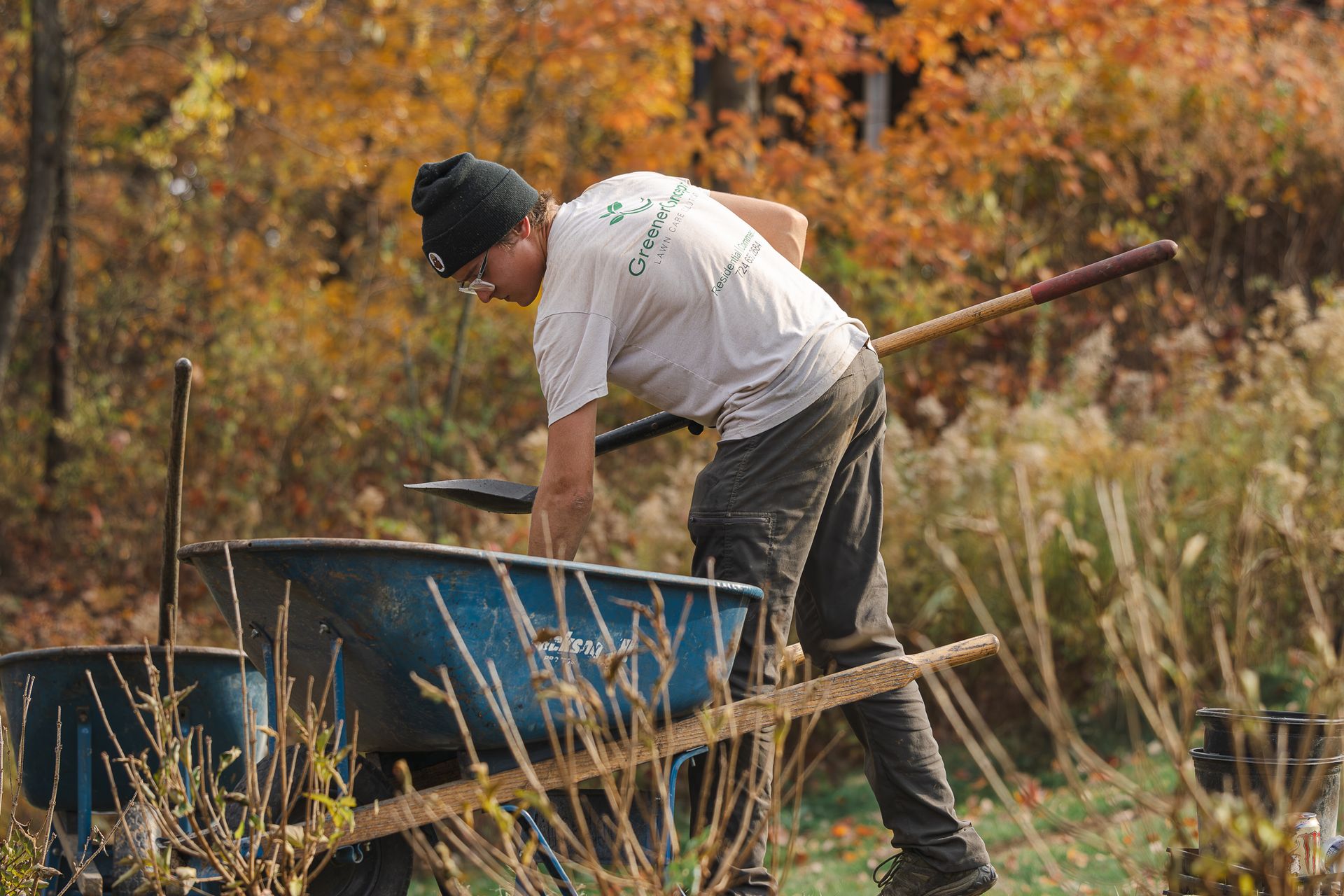 A man is pushing a wheelbarrow with a rake.