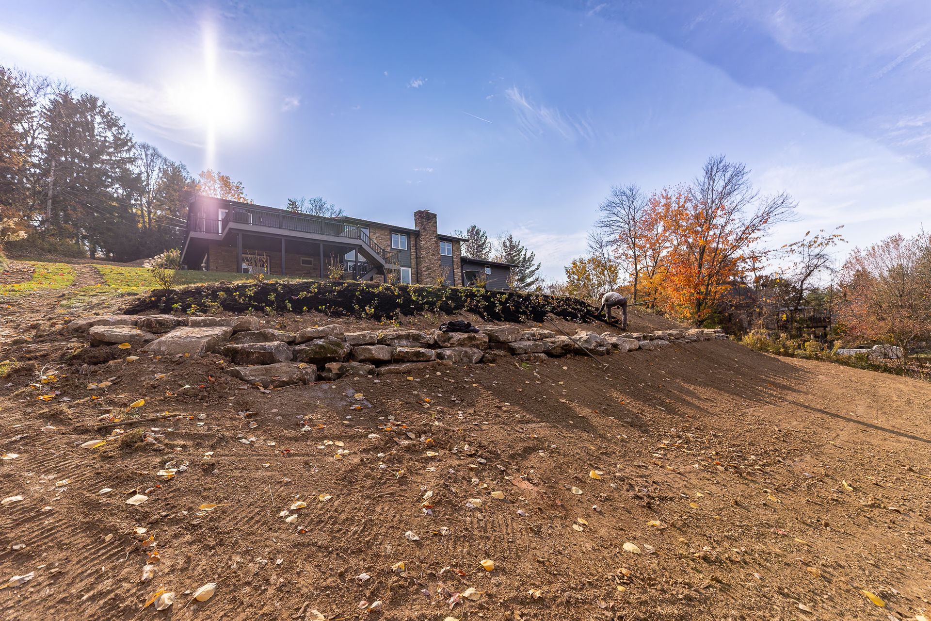 A large house is sitting on top of a hill next to a dirt field.