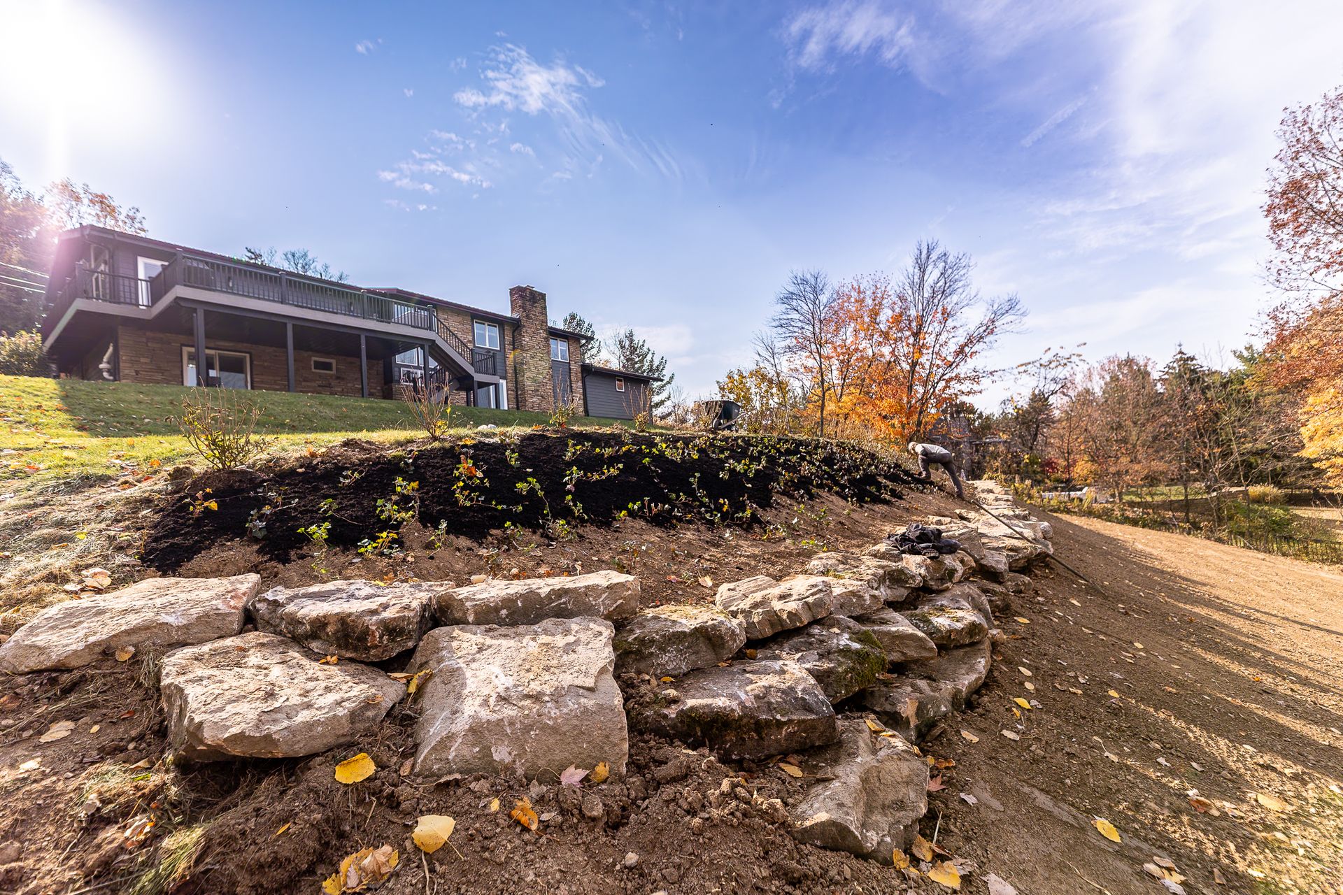 A large house is sitting on top of a hill next to a rock wall.