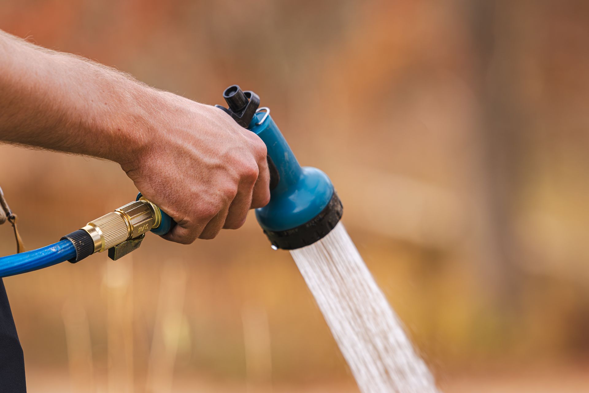 A man is watering a plant with a hose.