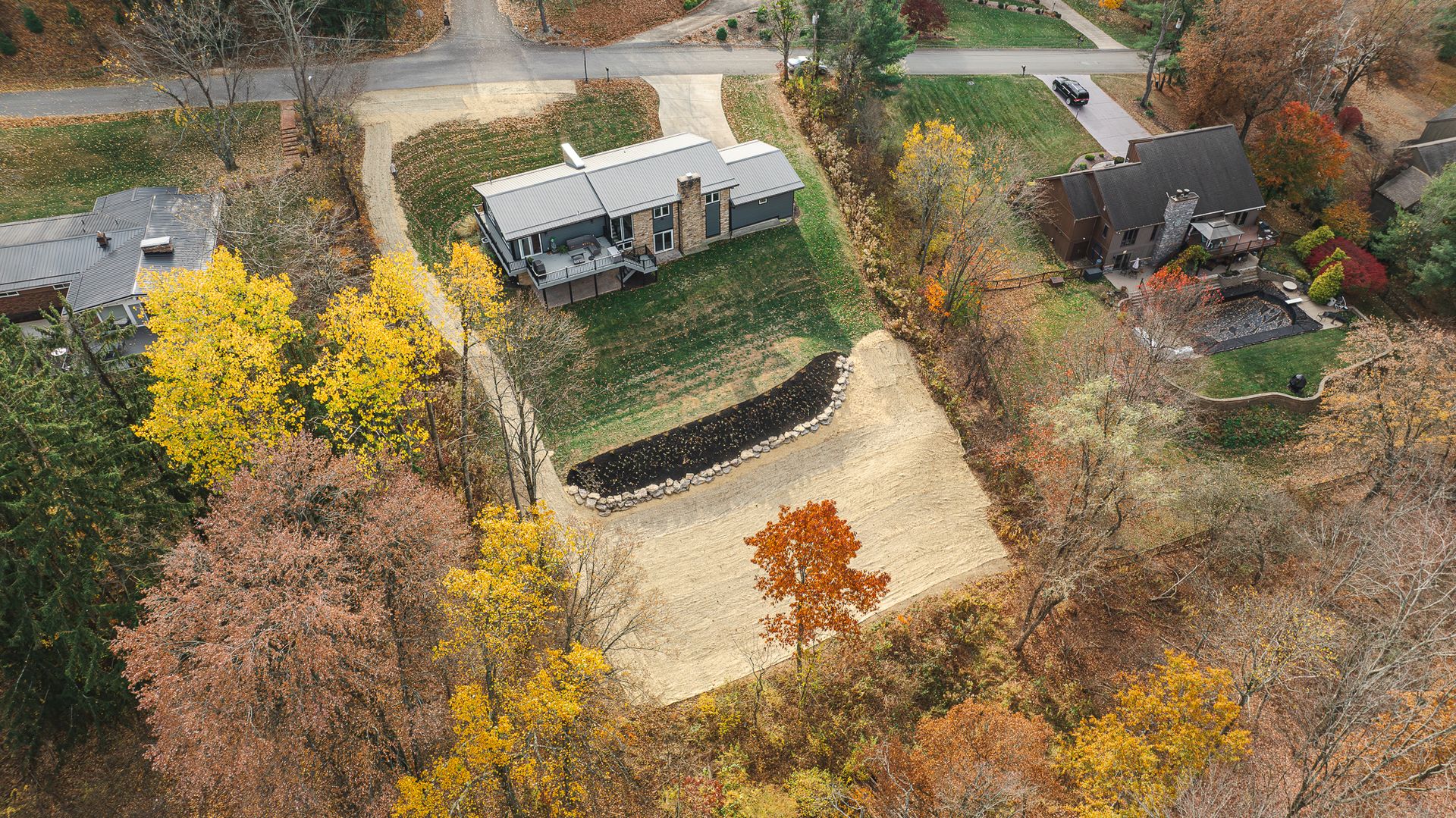 An aerial view of a house surrounded by trees and a road.