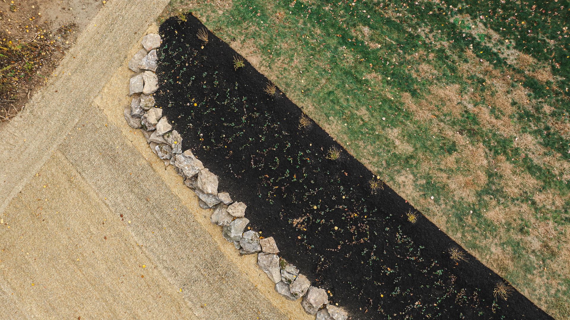 An aerial view of a dirt road next to a field of grass.