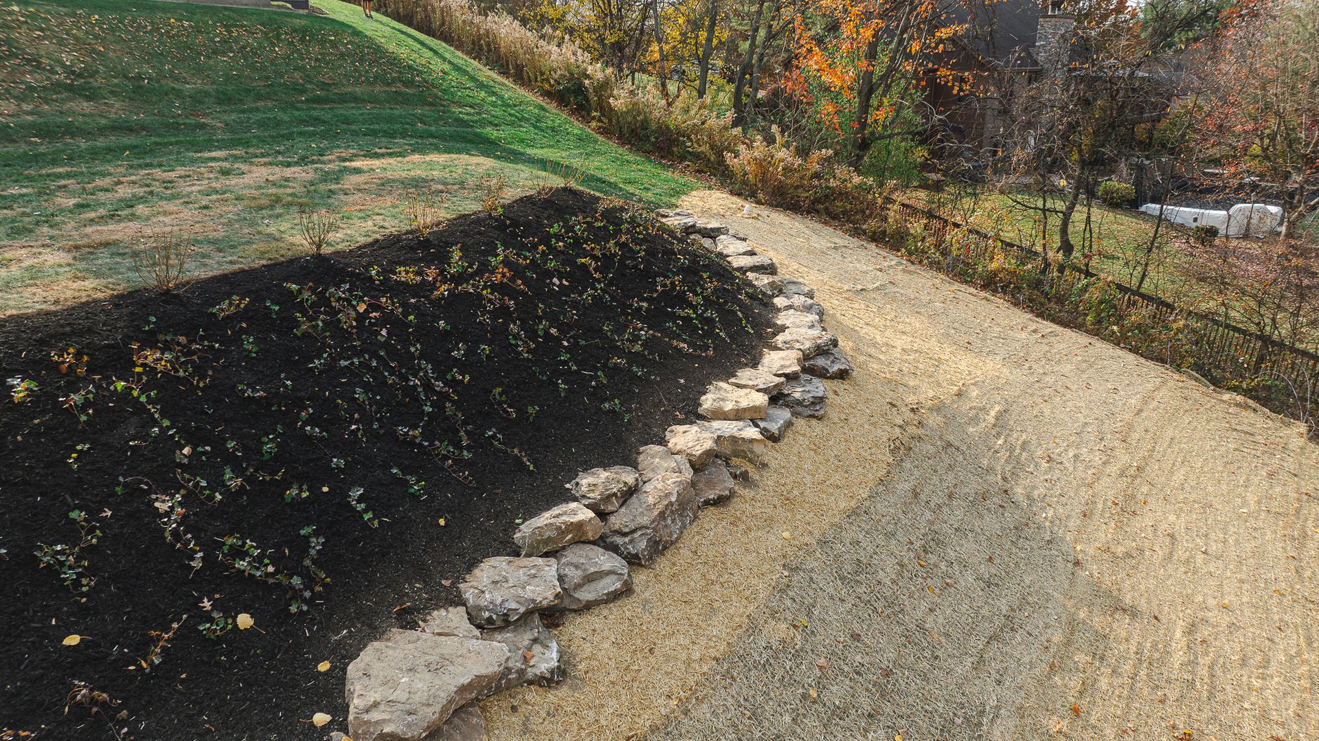 A gravel path leading to a field with a rock wall.