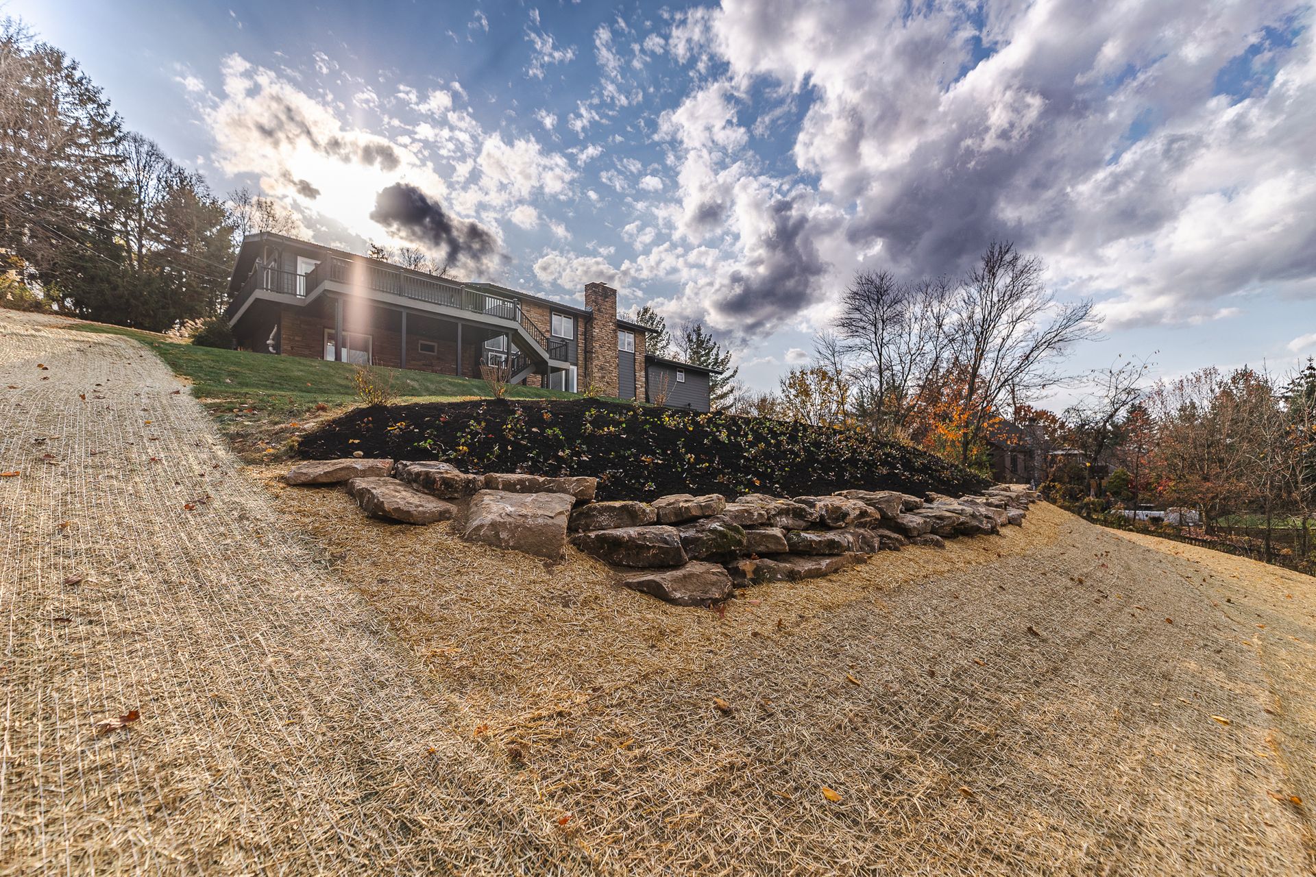 A large house is sitting on top of a hill next to a gravel road.
