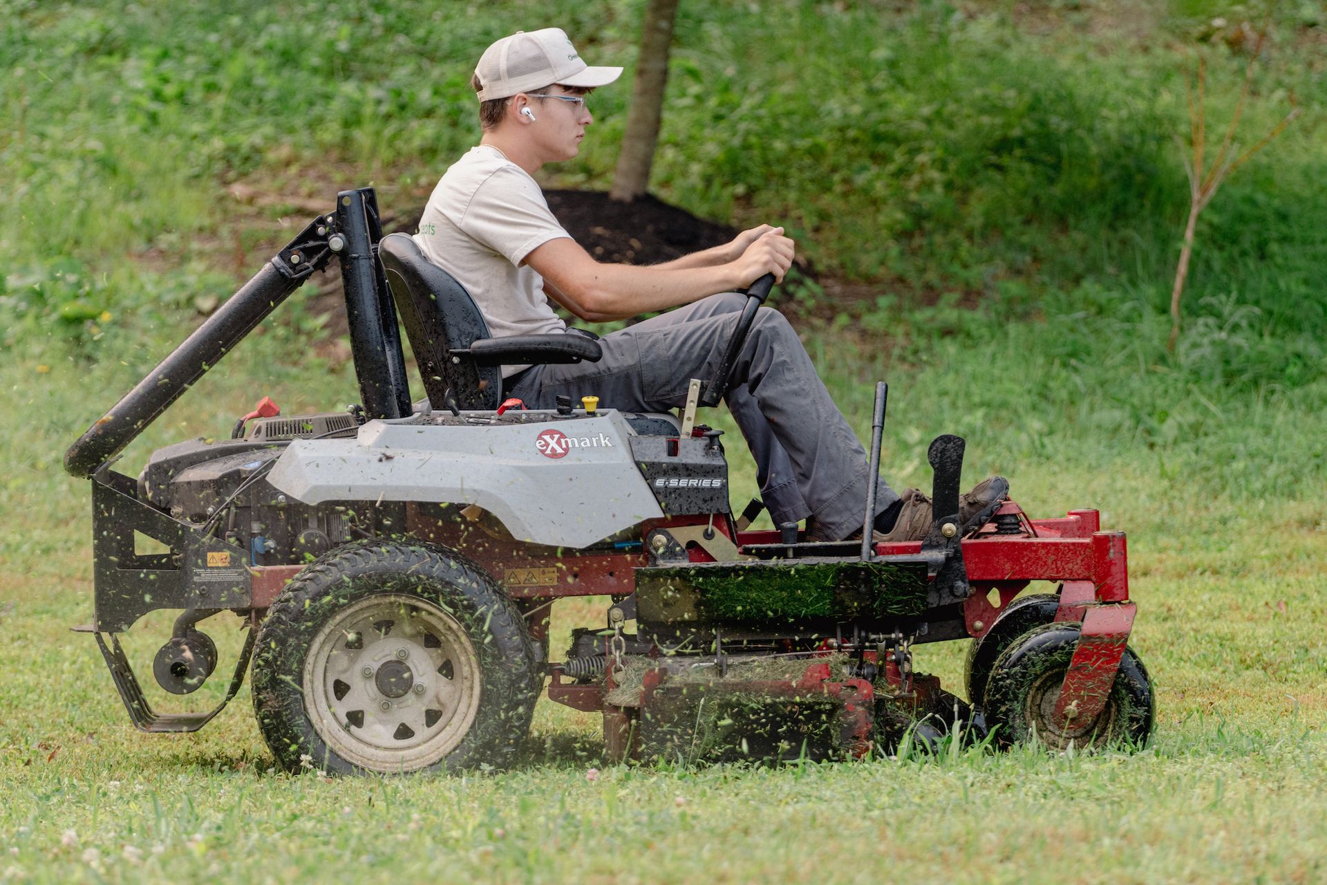 A man is riding a lawn mower on a lush green field.