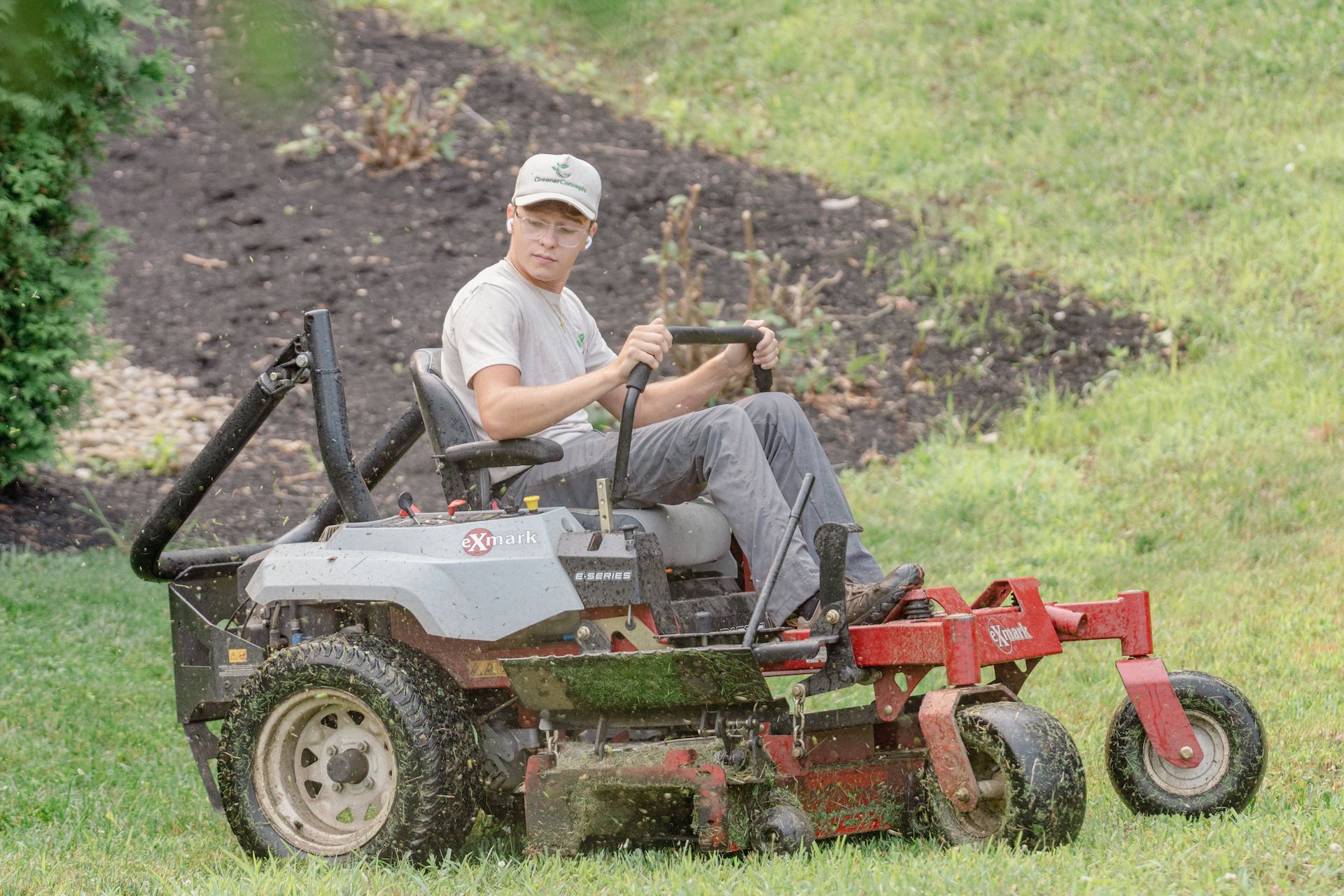 A man is riding a lawn mower on a lush green lawn.