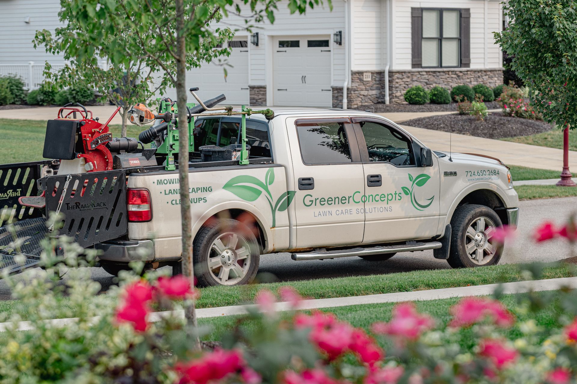 A white truck is parked on the side of the road in front of a house.