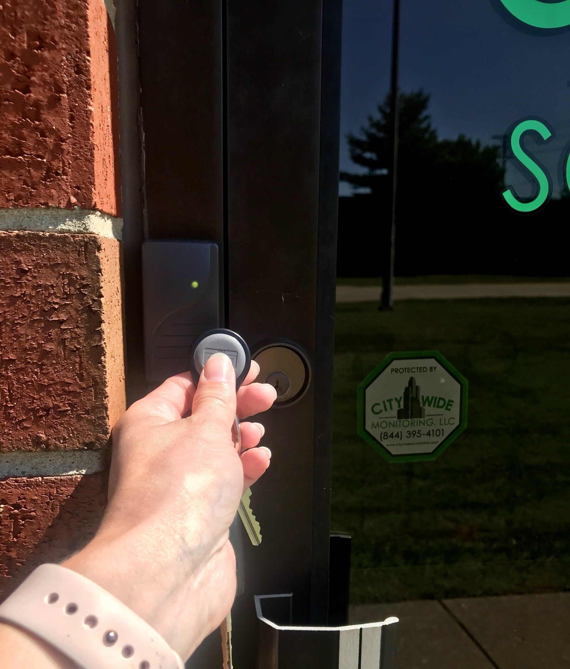 A person is holding a key in front of a door that has a sticker on it that says citywide