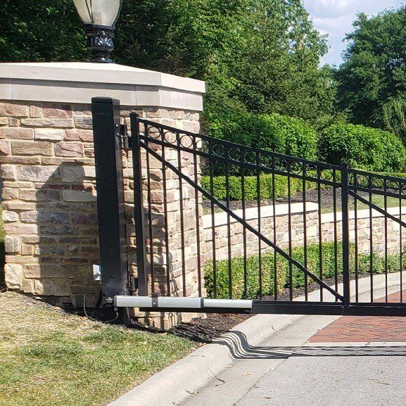 A black wrought iron gate with a brick wall in the background