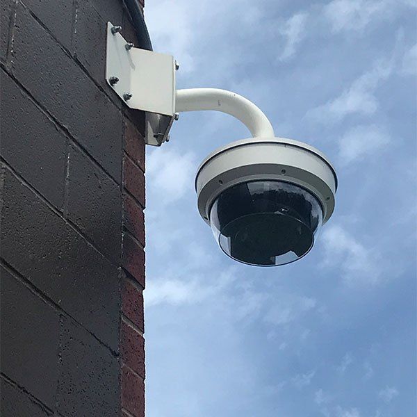 A security camera is mounted on the side of a brick building.