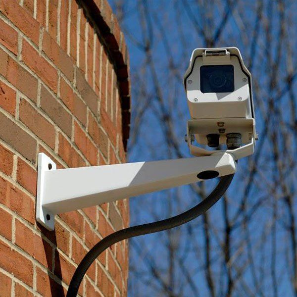 A security camera mounted on the side of a brick building