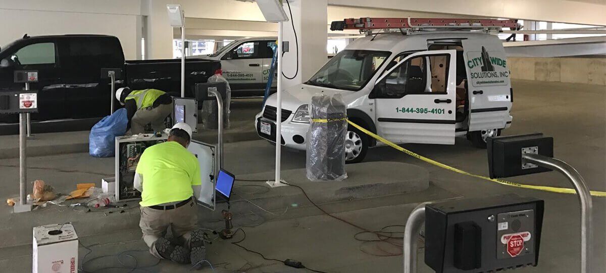 A group of men are working in a parking garage next to a van.