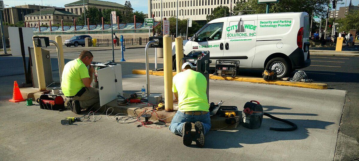 Two men are working on a parking meter in front of a white van.