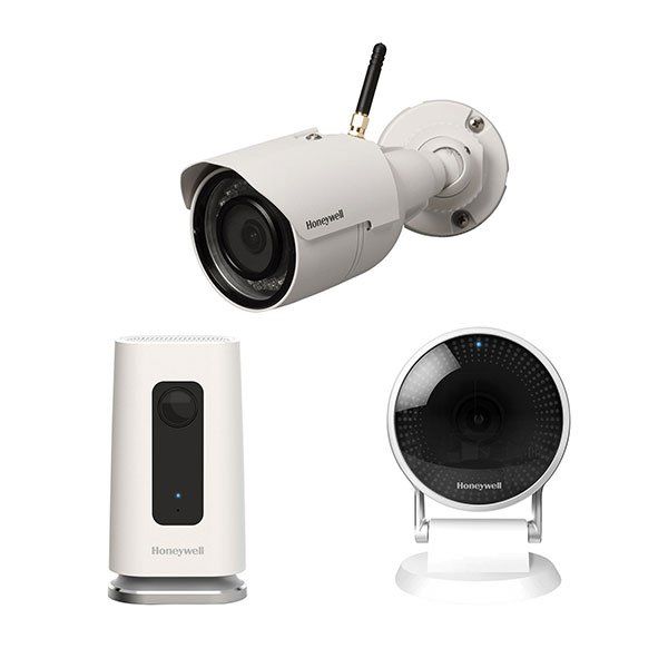 A honeywell security camera is sitting next to two other cameras