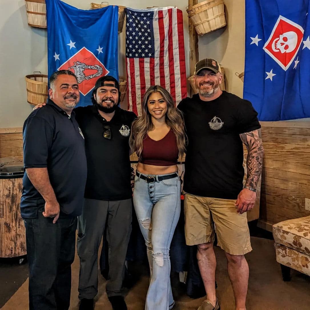 A group of people are posing for a picture in front of an american flag.