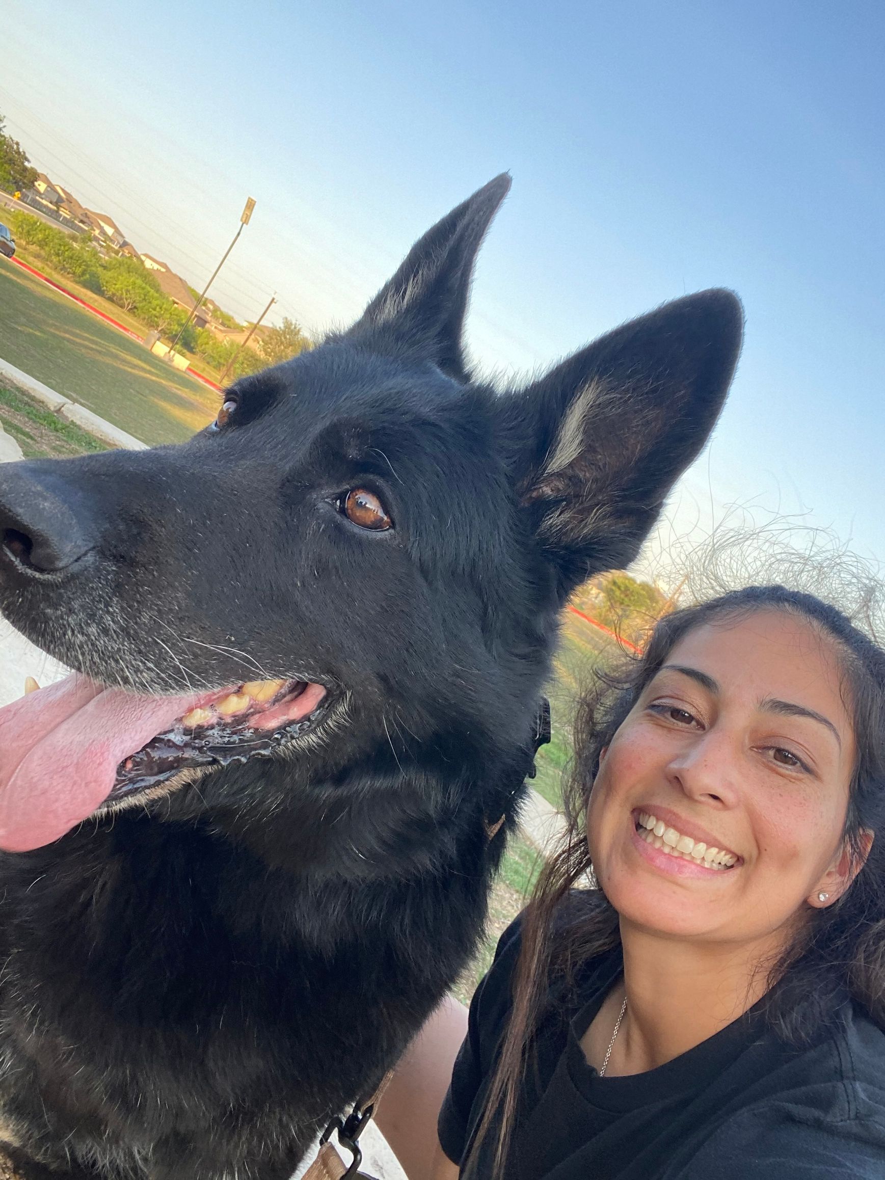 A woman is taking a selfie with a black dog.