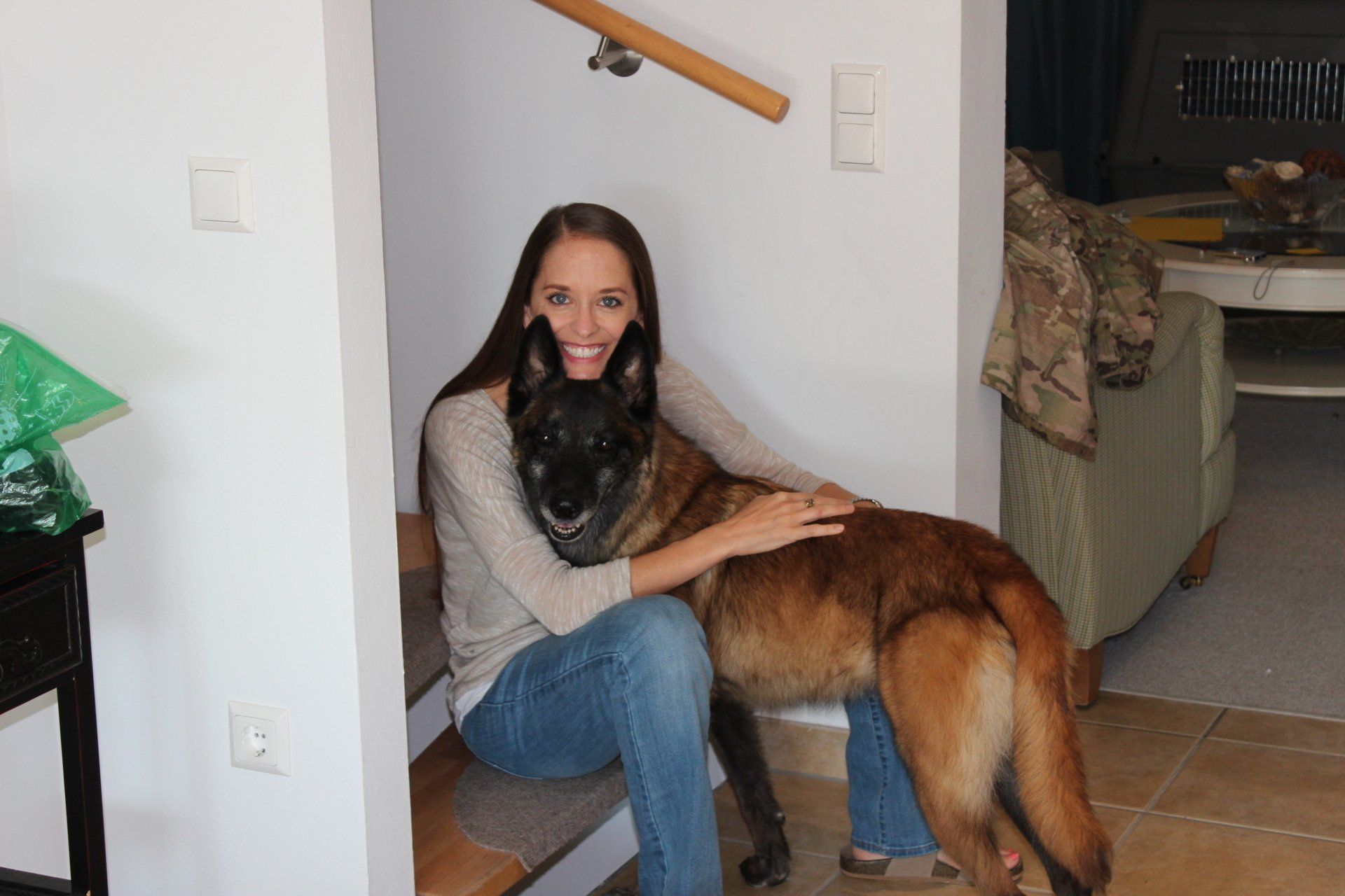 A woman is sitting on a staircase with a dog on her lap.