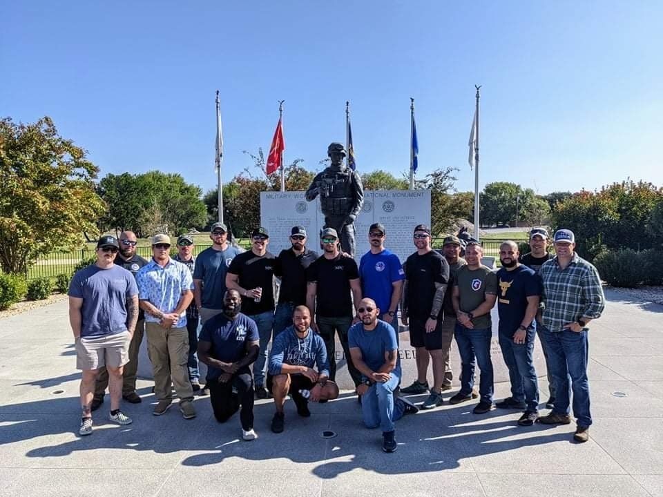 A group of men are posing for a picture in front of a statue.