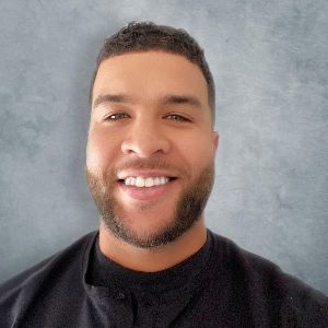 A man with a beard is smiling for the camera while wearing a black shirt.