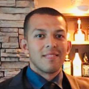 A man in a suit and tie is standing in front of a bar.