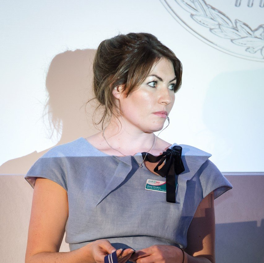 A woman in a grey dress with a name tag that says ' castrol ' on it