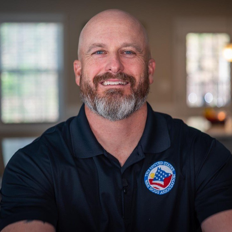 A bald man with a beard is wearing a black shirt with an american flag on it