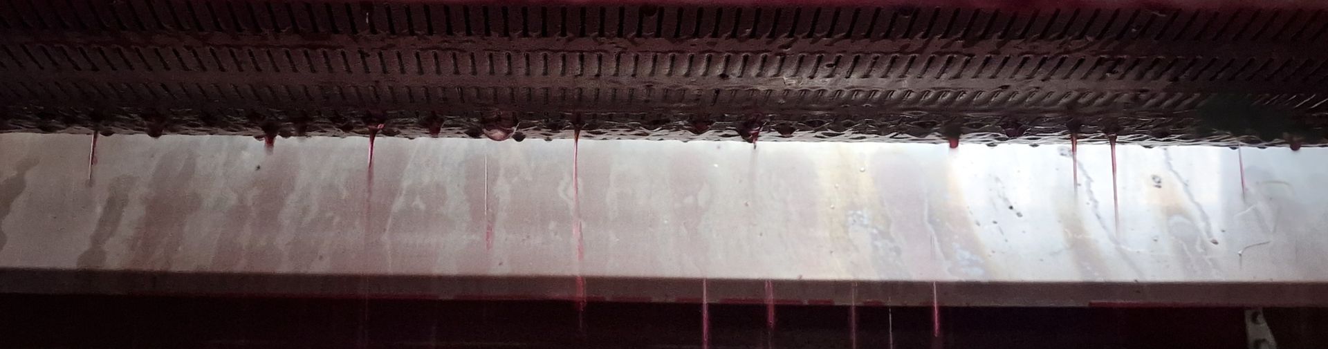 Un gros plan d'une surface métallique avec un liquide rouge qui en sort.