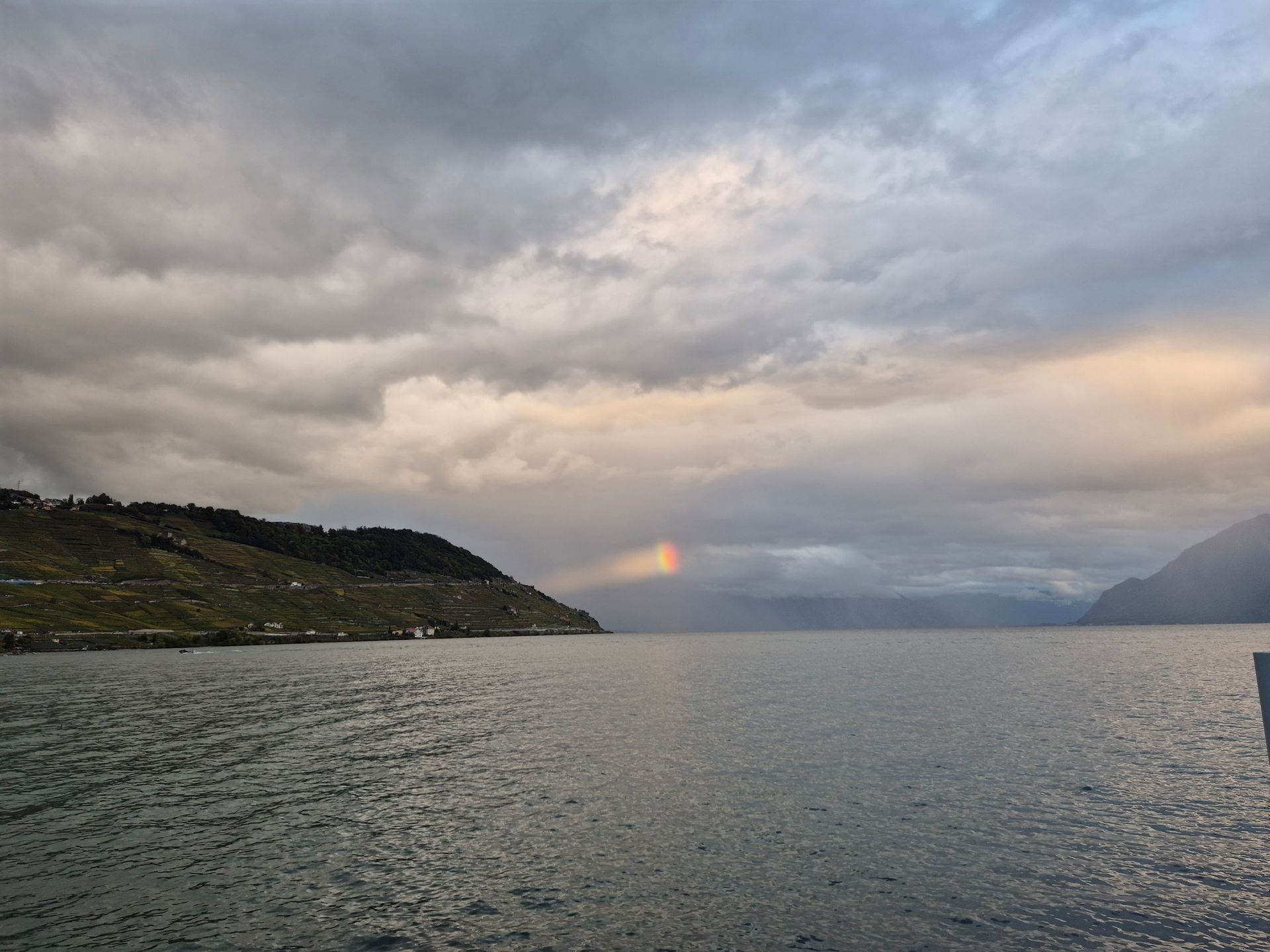 Un lac avec des montagnes en arrière-plan et un arc-en-ciel dans le ciel