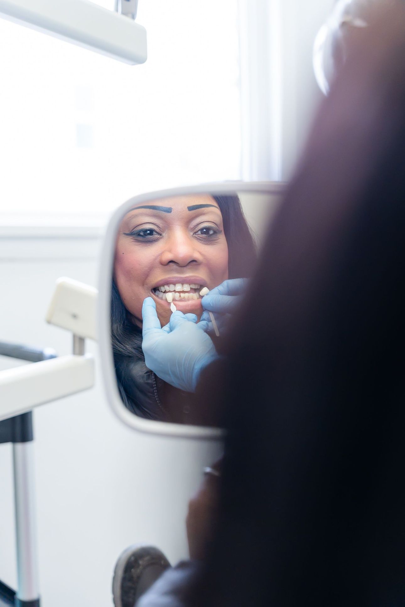 Patient smiling at her new smile in a hand mirror at Rome Dental