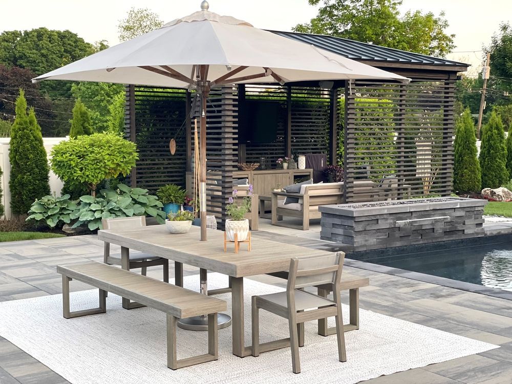 Modern outdoor patio with table, benches, umbrella, and a poolside lounge area