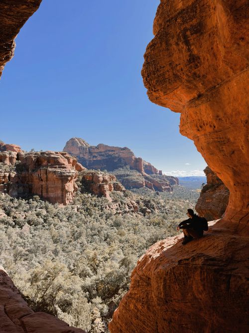 Red sandstone canyon framing a desert valley with shrubs and distant mesas under a clear sky